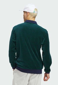 Polo à manches longues de couleur vert foncé avec de fines rayures horizontales. Doté d'un col et de poignets navy, d'une texture douce et d'une coupe décontractée.