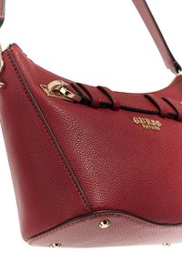 Sac en cuir texturé rouge avec des accents en métal doré, des détails en bord noir et une sangle de poignée supérieure.
