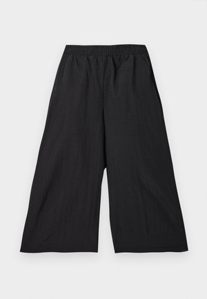 Μαύροι φαρδιοί cropped παντελόνες με ελαστική μέση, κατασκευασμένοι από ελαφρύ ύφασμα, απεικονίζονται σε φωτεινό φόντο.