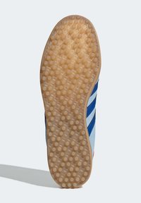 Semelle de sneaker en caoutchouc gomme texturé. Présente un motif en nid d'abeille et des accents bleu, blanc et rouge sur le côté.