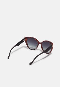 Gafas de sol de ojos de gato con montura de carey, lentes graduales grises y varillas texturizadas negras. Presenta sutiles acentos metálicos.