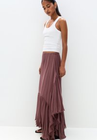 Maxi skirt in mauve, made of soft fabric. Features layered design with ruffled edges. Paired with a white fitted tank top.