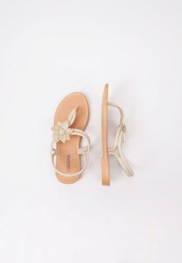 Chanclas beige con un acento texturizado floral y tiras delgadas. Suela marrón con el logo grabado. Acabado suave, diseño minimalista.