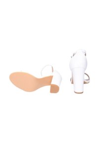 Sandali bianchi con tacco largo, punta aperta e cinturino alla caviglia. La suola è di colore beige con una trama antiscivolo. Finitura sintetica liscia.