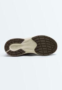 Sole of a sneaker with beige midsole and brown textured rubber outsole featuring tread patterns for traction and grip.