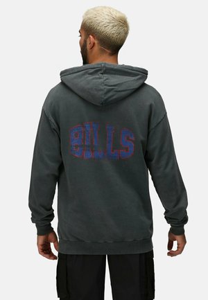 Sweatshirt à capuche gris foncé avec un graphisme texturé et audacieux "BILLS" en rouge et bleu au dos. Présente une coupe décontractée et des bords côtelés.