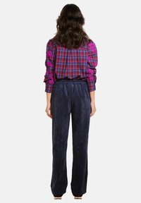 Ražu apģērbs ar purpursarkanu un zilu pārbaudi, ar izrakumiem piedurknēm, apvienots ar tumši ziliem korduroja biksēm, kurām ir elastīga josta.