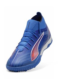 Zapatilla deportiva azul con parte superior texturizada, diseño angular, cierre de cordones y un atrevido acento rojo en el lateral. Suela de goma con patrones de agarre.