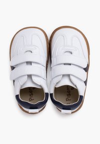 Scarpe bianche per bambini con due strap in velcro, dettagli blu navy, superficie liscia, punta rotonda e suola in gomma marrone.