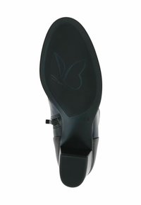 Semelle de chaussure en cuir noir avec une semelle en caoutchouc texturée. Présente un logo papillon et un design de talon bas et rectangulaire.