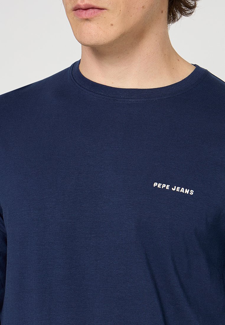 Camiseta de cuello redondo azul marino hecha de tela suave, con un pequeño logo blanco de "Pepe Jeans" en el lado izquierdo del pecho.