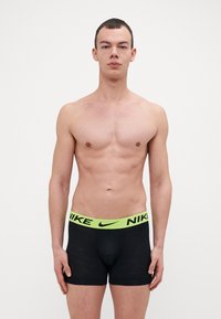 Sorte boxershorts med en limegrønn Nike-logo i livet. Stoffet ser jevnt ut med en tettsittende passform, minimal merking ellers.