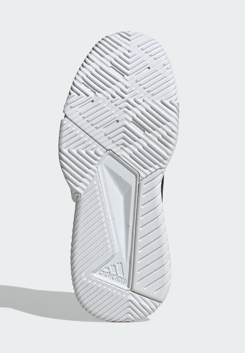 Semelle de chaussure avec un motif en chevrons texturé et des motifs verticaux, principalement blanche avec un accent noir et un détail de logo en relief.