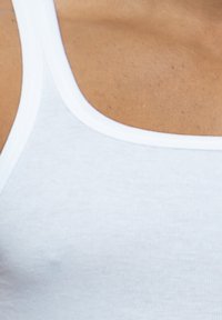 Top bianco senza maniche con scollatura a barca e spalline sottili, realizzato in morbido e leggero tessuto di cotone, con una leggera trama a coste.
