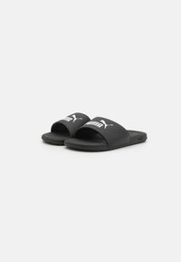 Sorte slidesandaler med åben tå. Fremstillet af syntetisk materiale, med en bred rem der har et hvidt Puma-logo og en tekstureret sål.