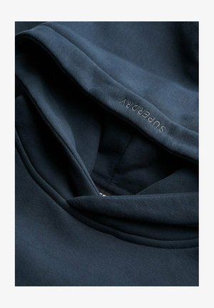 Dark blue hoodie with a soft fabric texture and a relaxed hood. The brand name "Superdry" is subtly embroidered on the inner seam.