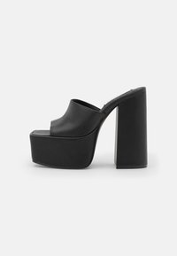 Mule à plateforme noire avec talon haut épais et bout ouvert, dessus lisse, présentée sur fond blanc uni.