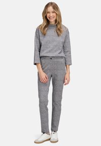 Haut à carreaux gris et pantalon assorti, tous deux en tissu texturé. La tenue comprend un col rond et des manches larges, associée à des baskets blanches.