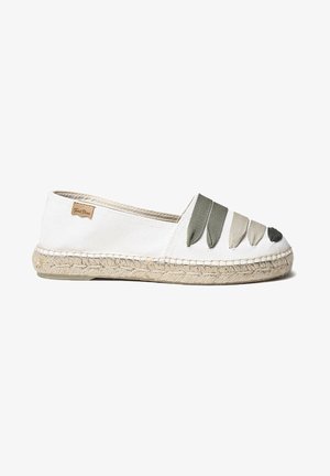 Alpargata blanca de lona con suela de yute tejida y cinco aplicaciones de tela con forma de hoja en verde, beige y negro en la parte superior.