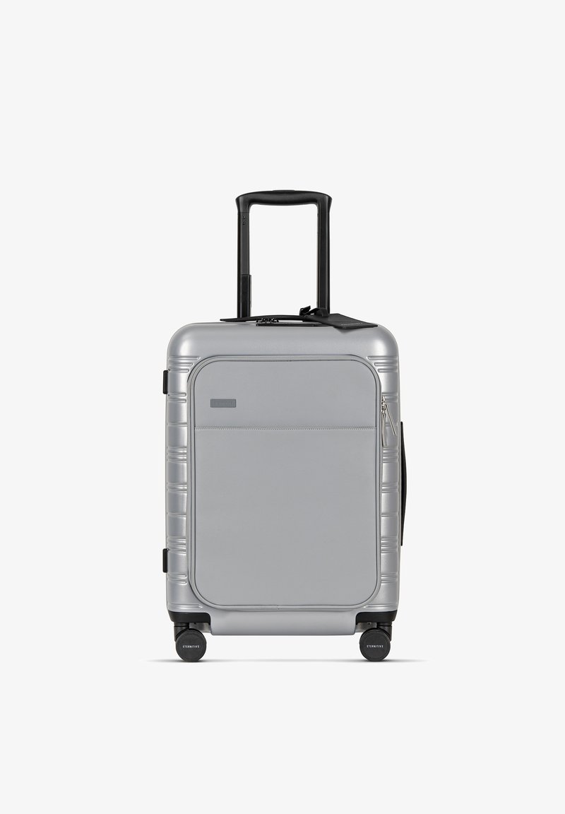 Silberner Hartschalenkoffer mit einem eleganten rechteckigen Design, ausziehbarem Griff, Reißverschlusstasche und vier leichtgängigen Rollen.