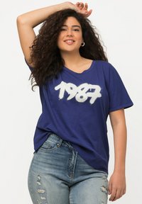 Tmavě modré tričko s krátkým rukávem s bílým graffiti "1987" na přední straně, vyrobené z jemné, lehké tkaniny.