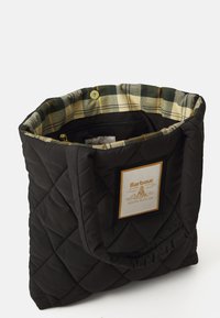 Fekete steppelt táska párnázott fogantyúkkal, kockás bélés és egy téglalap alakú Barbour South Shields logóval az elején.