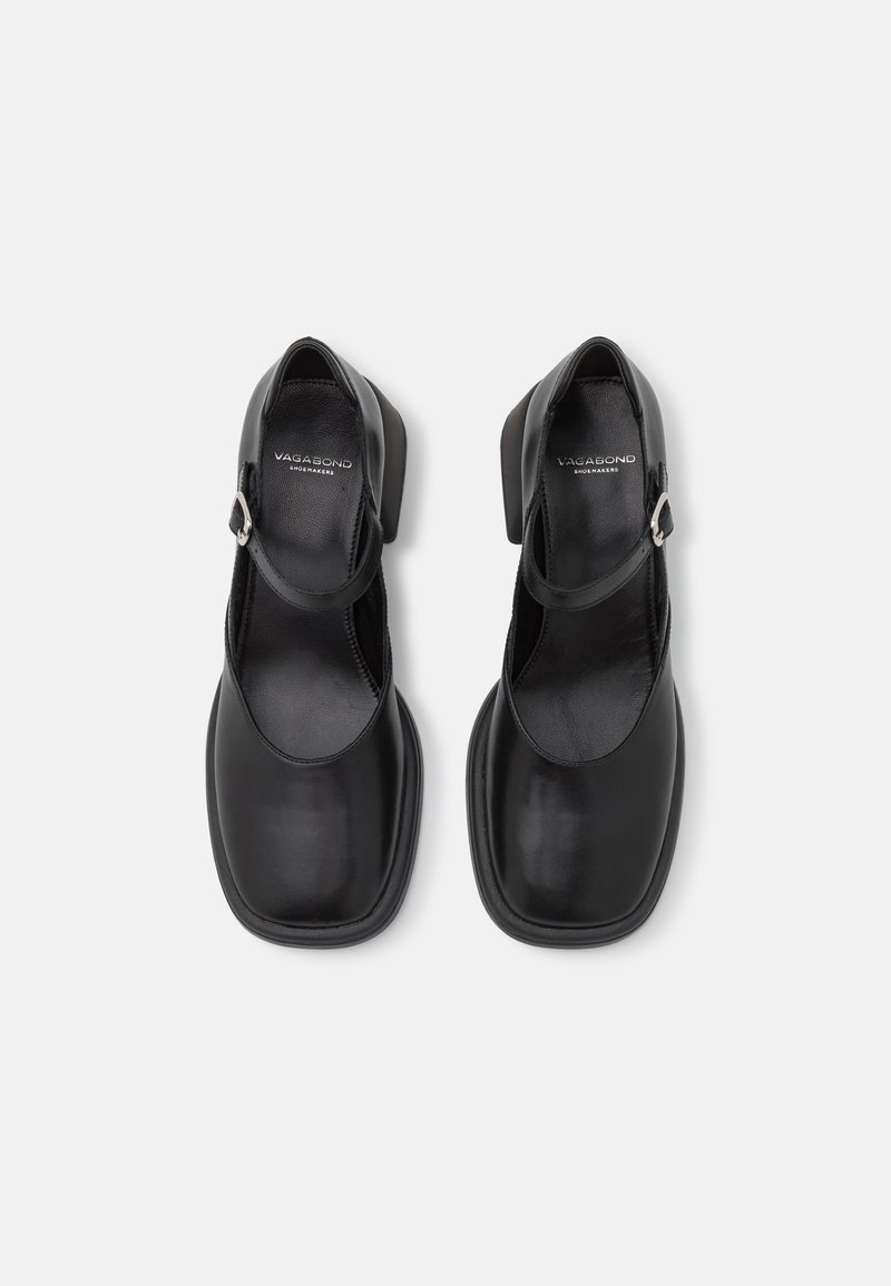 Chaussures en cuir noir avec un design à bout carré, une sangle Mary Jane et un petit talon carré. Texture lisse et style minimaliste avec une boucle métallique.
