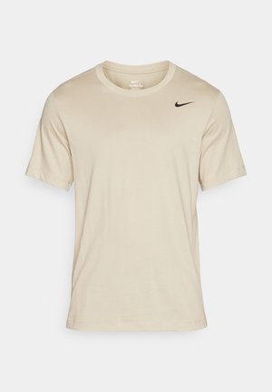 Beige short-sleeve t-shirt made of soft fabric, featuring a round neckline and a black Nike logo on the left chest. Smooth texture.