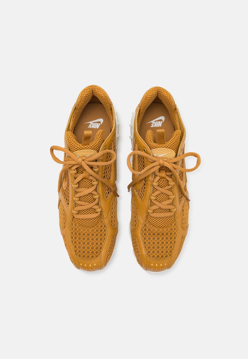 Baskets basses en cuir marron-orange avec des panneaux en maille, bout arrondi, lacets et semelles à motifs. Logo Nike sur la languette et sur le côté.
