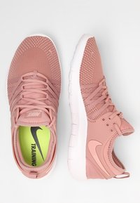 Buty do treningu Nike w miękkiej różowej siateczce z teksturowanym wierzchem, białą gumową podeszwą i wyrazistą zieloną wkładką z napisem "TRENING".