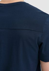 Tamsiai mėlynas marškinėliai su tekstūriniu viršutiniu skyriumi, trumpomis rankovėmis, glotniu apatine dalimi ir apvaliu iškirpimu.