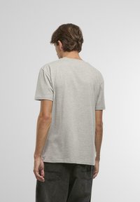 Šedé bavlněné tričko s kulatým výstřihem, krátkými rukávy a volným střihem. Žádné viditelné vzory nebo grafika; jednoduchý design s jemnou texturou.