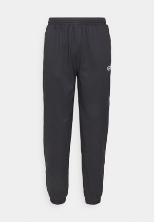 Zwarte joggingbroek gemaakt van een gladde stof, met een elastische tailleband en omslagmanchetten. Bevat een klein logo op de linker dij.