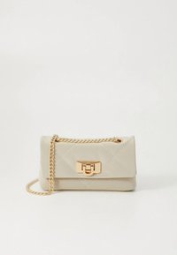 Beež tikandiga käekott, mis on valmistatud kunstnahast, kullarohelise kettidega ja ristkülikukujulise metallkinnitusega.