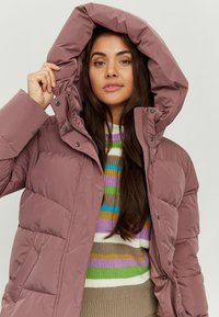 Puffy, light purple jacket with a hood, snap buttons, and side pockets. Worn over a multicolored striped sweater. Soft, smooth texture.