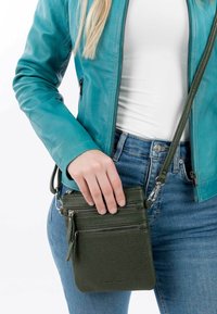 Green leather crossbody bag with three zippered pockets, textured surface, adjustable strap, and metal hardware.