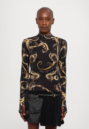 Maglia a maniche lunghe con base nera, motivo dorato a spirale e colletto alto. Abbinata a una gonna plissettata nera e a una tasca in pelle.