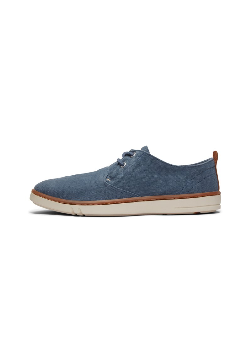 Zapato de lona azul con punta redonda, diseño con cordones, suela de goma crema y acento de cuero marrón en el talón. Superficie plana y texturizada.