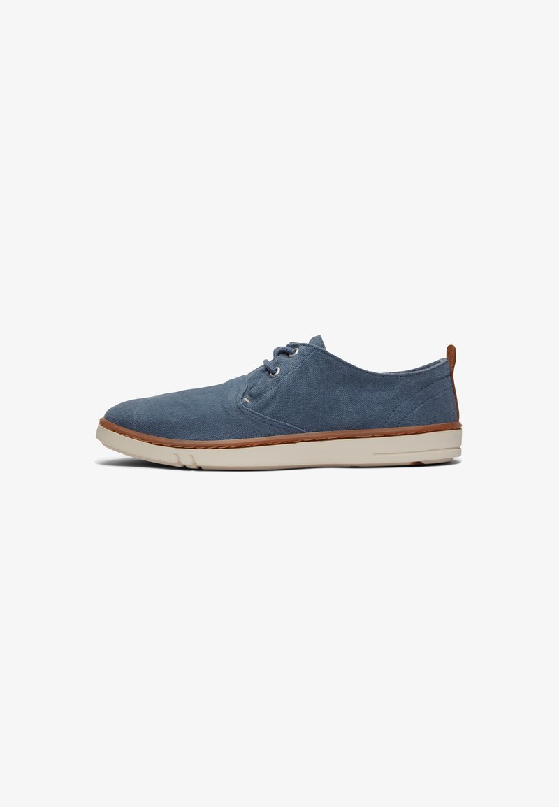 Blue canvas shoe with round toe, lace-up design, cream rubber sole, and brown leather accent at the heel. Flat, textured surface.