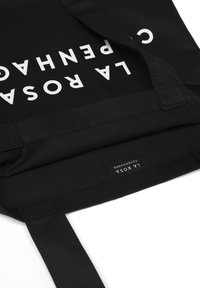 Borsa tote nera in tessuto, con stampa bianca in caratteri audaci "LA ROSA COPENHAGEN." Include manici robusti e un interno etichettato.