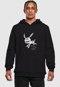 Black hoodie featuring a white, hand-drawn rabbit design with red eyes and text reading "WALK IN THE DARK." Soft cotton fabric, kangaroo pocket.