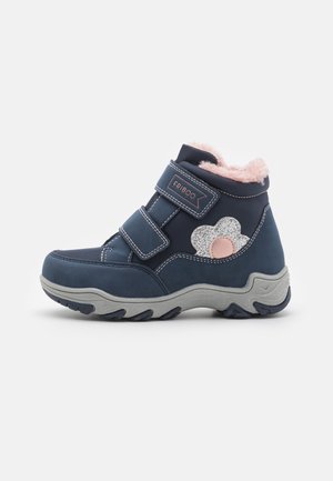Botte d'hiver pour enfants bleu marine avec double fermeture velcro, doublure en polaire rose, semelle grise et décoration en forme de fleur argentée scintillante.