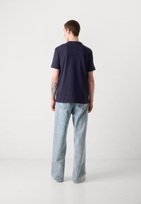 Marineblå t-skjorte med kortermet, av bomullmateriale, avslappet passform, kombinert med lyseblå, løstsittende jeans, med standard lommer og lys vask.