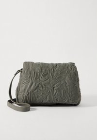 Grå vadderad läderväska med blommig brodyr, rundad form och tunn axelrem. Texturerad yta är framträdande.