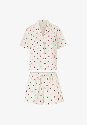 Weißes kurzärmeliges Hemd mit Knöpfen und Shorts mit elastischem Bund, bedruckt mit einem Muster aus roten Herzen.