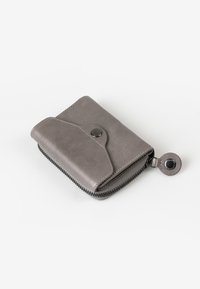 Portafoglio in pelle grigia con chiusura a zip, bottone a pressione e angoli arrotondati. Presenta cuciture visibili e una linguetta laterale.