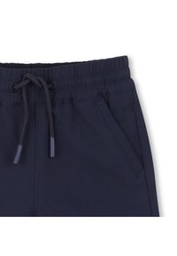 Φόρμες σε ναυτικό μπλε με ελαστική μέση και κορδόνι, διαθέτουν δύο πλαϊνές τσέπες και υφή λείου, ελαφρώς υφασμένου υφάσματος. Η ελαστική μέση προσφέρει άνεση.