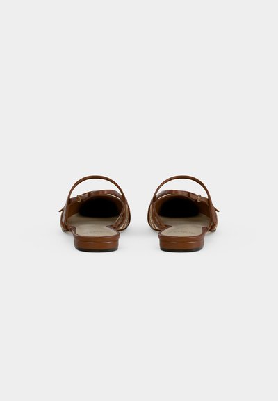 Ζευγάρι καφέ δερμάτινα σανδάλια με ανοιχτά δάχτυλα και λουράκι πίσω, από πίσω σε λευκό φόντο.