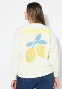 Crèmekleurige gebreide trui met grote tekst "LEMON" en gele citroenen met blauwe bladeren op de rug; ribgebreide mouwen en zoom.