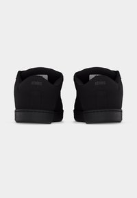 Ζευγάρι μαύρα αθλητικά παπούτσια χαμηλού προφίλ, με θέα από πίσω, που έχουν μαλακά περιλαίμια και το λογότυπο «etnies» στις ταμπέλες της φτέρνας.